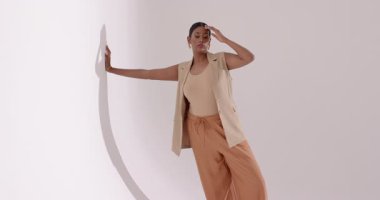 Beyaz sahne arkası çekimlerine karşı bej kıyafetli Hintli kadın manken dokunuşu. Zarafet, profesyonellik, minimalizm, güzellik, hareket, çok yönlülük, stüdyo