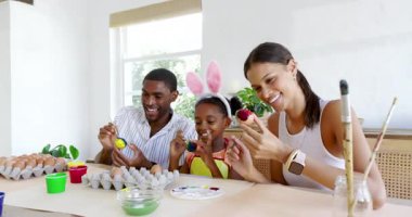 Çeşitli aileler evde Paskalya yumurtalarını boyuyor, yaratıcı tatil aktivitelerinin tadını çıkarıyorlar. çeşitli aile zamanları, yaratıcılık, gelenek, birliktelik, kutlama, el işi