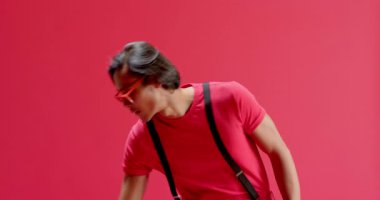 Meraklı Asyalı adam kırmızı çerçeveli güneş gözlüğü kaldırıyor sonra da stüdyoda çömelmiş kırmızı küreyi inceliyor. Minimalist, enerjik, meraklı, modern, zanaatkar, stil sahibi, düşünceli.