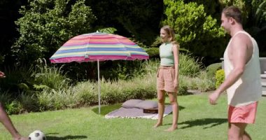 Çimenlikte selamlaşma, çeşitli arkadaşlar futbol topu paslıyor, top sürüyor, hokkabazlık yapıyor ve ayak çalışması yapıyor. Açık hava eğlencesi, takım sporu, gündelik yaz, atletik aktivite, eğlence, arkadaşlık, canlılık.