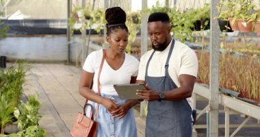 Çocuk odasında, erkek tablette serada tartışırken kadınlara bitkileri gösteriyor. Bahçıvanlık, bahçıvanlık, teknoloji, takım çalışması, işbirliği, dijital