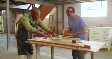 Meydan okuduktan sonra, Afrikalı Amerikalı erkek marangozlar kürsüde toplanmak için yönetim kurullarına rehberlik ediyor ve işaret koyuyorlar. İşçilik, akıl hocalığı, işbirliği, atölye, hassasiyet, el işi, sanayi