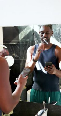 Dikey video: Adam banyo aynasında dişlerini fırçalıyor, sabah rutinine odaklanıyor. Hijyen, bakım, yansıma, günlük ritüel, kişisel bakım, tazelik.