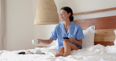 Yatakta dinlenen, pijamalı bir kadın sabah kahvesinin keyfini çıkaran gülümsemeli, evde, fotokopi çeken bir kadın. Rahatla, rahatla, rahatla, uyan, mutluluk