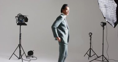 Sola adım attıktan sonra, Asyalı erkek manken yürüyüş merkezi modellik için stüdyo ceketini ayarlıyor. Profesyonel, moda, minimalist, sofistike, erkek, stil, portre