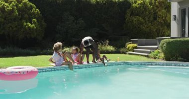 Aile evden çıkıp havuza doğru yürüyor, serinlemek için neşeyle suyu tekmeliyor. Aile, eğlence, açık hava, oyun, rahatlama, yaşam tarzı, arka bahçe.