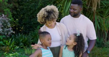 Bahçe tezgahının yanında bekleyen farklı bir aile, kızı sağı işaret ediyor, anne ve babası onu takip ediyor. Aile, açık hava, neşe, bağlantı, doğal mutluluk, boş zaman