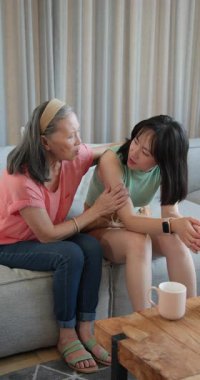 Dikey video: Yaşlı bir kadın, genç bir kadını kanepede rahatlatıyor, evdeki destekleyici anı paylaşıyor. empati, dostluk, terapi, bağlanma, duygusal, önemseme