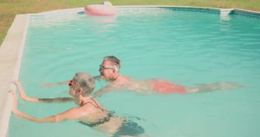 Olgun bir çift havuzda dinleniyor, içkilerin ve güneşin tadını çıkarıyorlar. Tatil, tatil, rahatlama, yaz, lüks, yüzme.