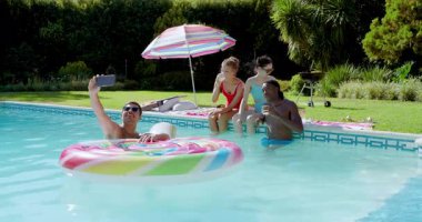 Havuzda yüzen, selfie çeken, akıllı telefonlardan geçen ve fotoğraflara bakan farklı arkadaşlar. Açık hava, boş zaman, kutlama, yaşam tarzı, canlı, birliktelik, gündelik