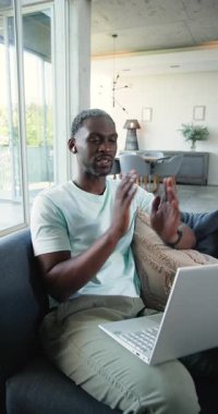 Dikey video: Evde dinlenmek, kanepede dizüstü bilgisayar kullanmak, boş zamanların tadını çıkarmak. Yaşam tarzı, teknoloji, konfor, oturma odası, günlük, evden çalışma