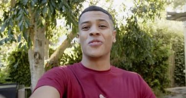 Erkek vlog kaydedicisi verandada lensli akıllı telefonu tutuyor, konuşuyor, el sallıyor ve güncellemeleri paylaşıyor. Doğa, yaşam tarzı, samimi, açık hava, rahatlama, iletişim, canlı