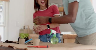 Gülümseyen, çeşitli çiftler mutfakta birlikte çiçekleri suluyor, evde boş vakitlerin tadını çıkarıyorlar. Bahçıvanlık, yaşam tarzı, hobi, takım çalışması, kaynaşma