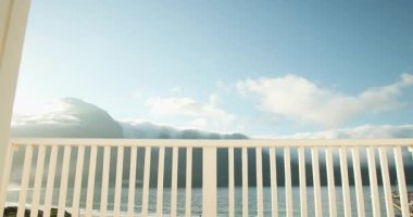 Açık balkon kapısı berrak mavi gökyüzü ve sakin okyanus manzarasını gösteriyor, boşluğu kopyala. Manzara, sükunet, deniz, kıyı, rahatlama, ufuk