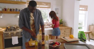 Çeşitli çiftler rahat mutfakta yemek hazırlıyor, tatilde evde yemek pişirme deneyiminin tadını çıkarıyorlar. Mutfak