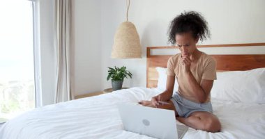woman shopping online with laptop and credit card on bed, at home. Online shopping, e-commerce, technology, relaxation, bedroom, internet