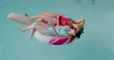 Havuzda yüzen çeşitli kadın arkadaşlar, su sıçratan adamların peşinden kürek çekiyorlar, sonra dinleniyorlar. Eğlence, yaz, eğlence, canlılık, arkadaşlık, açık hava, yaşam tarzı.