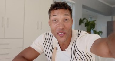 Erkek yetiştirme cihazı, kamerayı selamlama, mutfakta bitki ve dolaplarla işaret etme, çağrı jesti yapma. Profesyonel, iletişim, yaşam tarzı, gündelik, modern, neşe, ifade