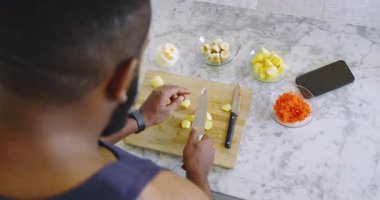 Afro-Amerikalı bir adam ananas dilimliyor sonra da tezgahta meyve suyu için sarı meyve koyarak fotokopi çekiyor. Sağlık, sağlık, beslenme, hazırlık, mutfak, yaşam tarzı, modern
