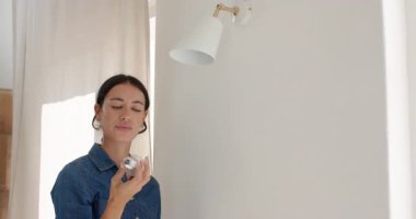 Kadın evdeki lambayı ayarlıyor, iç aydınlatmaya odaklanıyor, fotokopi çekiyor. Dekor, tasarım, ambiyans, aydınlatma, ayarlama