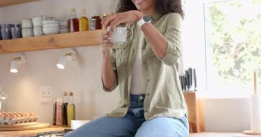 Kadın modern mutfakta kahveden zevk alıyor, gülümsüyor ve evde rahatlıyor. Rahatlama, mutluluk, sabah, yaşam tarzı, ev, çağdaş