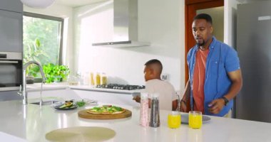 İşaret tabakları, Afrika kökenli Amerikalı baba ve oğlu adada baharatlı pizza servisi yapıyorlar. Aile, kaynaşma, ev yapımı, kahvaltı, neşe, etkileşim