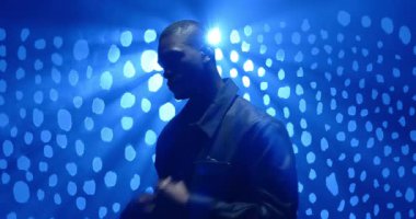 Stüdyoda Afrikalı Amerikalı bir adam mavi spot ışığı altında tapınak kaydırma profiline dokunuyor. Huysuz, iç gözlem, tiyatral, gradyan, minimalizm, ambiyans, duygu