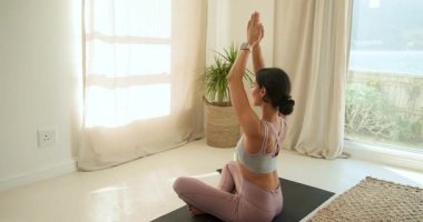 Evde yoga minderi üzerinde meditasyon yapan genç bir kadın huzur ve sükuneti kucaklıyor. Sağlık, meditasyon, farkındalık, rahatlama, dinginlik, zindelik