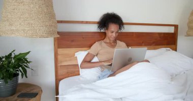 Yatakta dizüstü bilgisayarda çalışan bir kadın, odaklanmış ve üretken, evde. Ev ofisi, serbest çalışma, telekomünikasyon, teknoloji, yaşam tarzı, konsantrasyon.