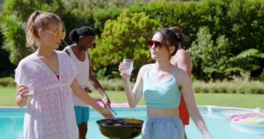 Çeşitli arkadaşlar mısır kızartıyorlar, turkuaz havuzunda dans ediyorlar ve arka bahçede müzik çalıyorlar. Kutlama, eğlence, açık hava, yaşam tarzı, canlılık, birliktelik, şenlik