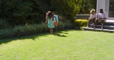 Aileler akıllı telefonlarıyla sohbet ederken çeşitli aile çocukları çimlerde durup futbol topuna saldırıyor. Aile, açık hava, oyun, yaşam tarzı, eğlence, etkinlik, modern