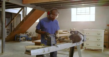 Afro-Amerikalı bir adam dükkânda torna işletiyor boş duruyor, dinleniyor, motor şekillendirmeye başlıyor. Sanatçı, marangozluk, atölye, endüstriyel, işçilik, manüel, mühendislik