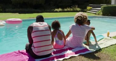 Güneşli bir günde arka bahçedeki havuza giriyorlar çeşitli aileler serinlemek için ayaklarına su sıçratıyorlar. Aile, eğlence, yaz, açık hava, mutluluk, yaşam tarzı, rahatlama.