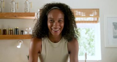 Mutfakta gülümseyen kadın evde yemek pişirmekten zevk alıyor, neşeli ve rahat hissediyor. Mutfak, ev işi, mutluluk, mutfak gereçleri, eğlence, yaşam tarzı