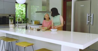 Çinli anne ve kız mutfakta yemek pişirmek için yeşil soğan doğruyor ve yumurta soyuyorlar. Aşçılık, aile, gelenek, işbirliği, yerli, sağlıklı, kırsal