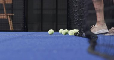 Beyaz kadın Padel kortunun arkasına geçip raket kullanarak sarı topları temizliyor. Sporcu, atletik, aktif, eğlence, eğlence, eğitim, fitness
