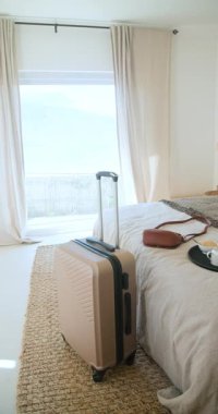 Dikey video: Elinde bavul, kahve ve akıllı telefonla otel odasında dinlenen bir kadın. Rahatlama, tatil, tatil, yaşam tarzı, varış yeri, turizm
