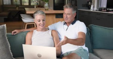 Olgun çift koltukta dinleniyor, evde dizüstü bilgisayara bakarken gülümsüyor. teknoloji, rahatlama, mutluluk, oturma odası, son sınıf, yaşam tarzı