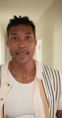 Dikey video: Gülen adam içeride komik surat yapıyor, günlük çizgili gömlek giyiyor. Portre, oyuncu, ifade, mutluluk, erkek, mizah