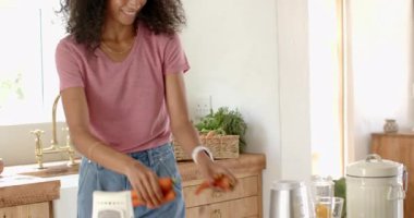 Evde sıcak mutfakta taze meyve suyu hazırlayan, havuç ve portakal doğrayan bir kadın. Yemek pişirme, sağlıklı beslenme, tazelik, yaşam tarzı, hazırlık