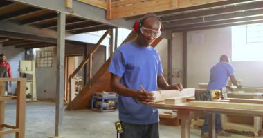 Tahtayı işaretleyen yapboz toplayan Afrikalı erkek marangoz dükkanda rehber olarak çalışmaya devam ediyor. Sanatçı, marangozluk, kesinlik, atölye, sanayi, işçilik, işbirliği