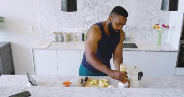 Modern mutfakta limon, havuç, bıçak ve fotokopi malzemelerini karıştıran Afro-Amerikalı bir adam. Blender, limon, havuç, minimalist, yemek pişirme, hazırlık, sağlıklı