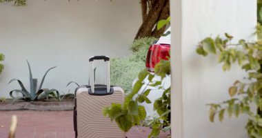 Garaj yolunda arabanın yanında duran bavul, değişik çiftlerin tatiline hazır. Seyahat, yolculuk, macera, yolculuk, kaçış, rahatla