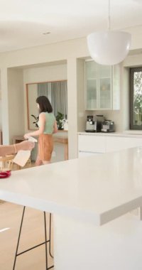 Dikey video: Yaşlı kadın mutfak tezgahını sprey şişeyle temizliyor, evi düzenli tutuyor. Temizlik, temizlik, temizlik, ev işleri, hijyen, ev işleri.