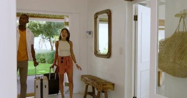 Mutlu çift tatil evine geliyor, gülümsüyor ve bavullarına sarılıyorlar. Seyahat, kaçamak, eğlence, romantizm, bavul, birliktelik