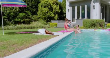 Arka bahçedeki havuzda oturan farklı arkadaşlar bacakları sallayarak tablet içeriğini paylaşıyor, mekanı kopyalıyorlar. Eğlence, eğlence, açık hava, rahatlama, arkadaşlık, yaz, canlı