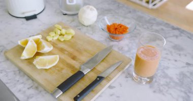 Kamera sağa ve aşağı doğru başlıyor, kesme tahtasını turuncu takozlar ve zencefil küpleriyle gösteriyor. Mutfak gereçleri, mutfak malzemeleri, tazelik, organik, kırsal, sağlıklı, yemek hazırlama