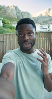 Dikey video: Afrikalı Amerikalı adam balkonda telefonla konuşuyor ve el sallıyor. Açık hava, yaşam tarzı, modern iletişim, boş zaman, kentsel, dikey video
