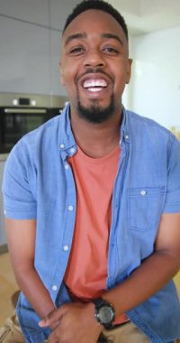 Dikey video: Afro-Amerikalı adamın gülümsemesi ve mutfaktaki fırını işaret etmesi. Modern, yaşam tarzı, samimi, rahat, içten, sıcak, dikey video