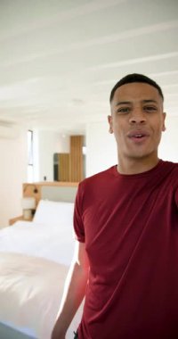 Vertical video: African American man tapping smartphone filming, panning glass door for room tour. Modern, minimalist, lifestyle, interior, home, natural, vertical video